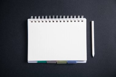 Beyaz kalem ve siyah arka plan üzerine not defteri.