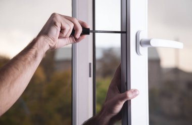 İnşaat işçisi tornavida ile pencere sabitleme. Yeni Plastik pencere içinde ev yükleme