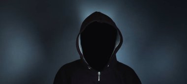 Koyu arka plan üzerinde hoodie duran yüzü olmayan adam.