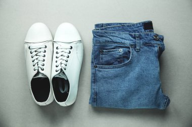 Mavi jeans ve gri arka plan üzerinde beyaz spor ayakkabı.