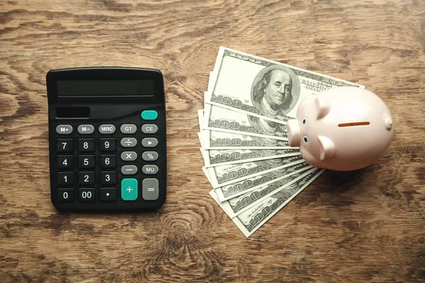 Piggy bank with money and calculator on wooden desk. Save your money