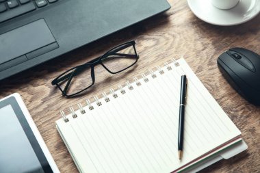 Ofis İşyeri. Dizüstü bilgisayar, Not defteri, ahşap masa üzerinde gözlük.
