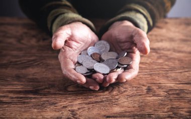 Yaşlı kadın sikkeler üzerinde ahşap masa gösterilen.