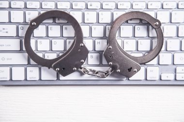 Bilgisayar klavye üzerinde kelepçe. Siber suç ve çevrimiçi dolandırıcılık kavramı