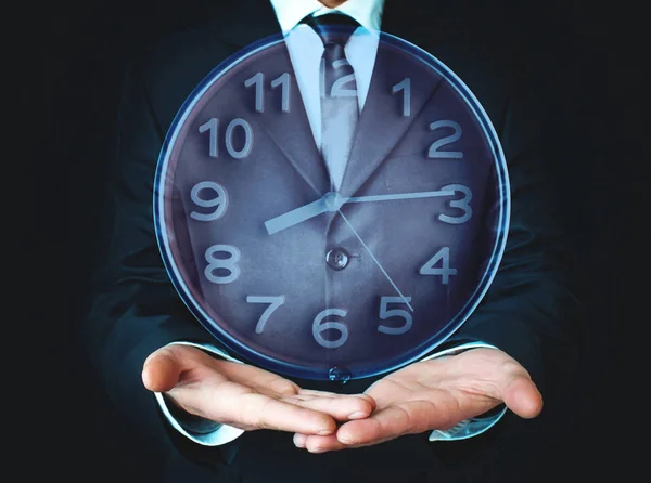 Бизнесмен держит часы. Управление рабочим временем  . — стоковое фото