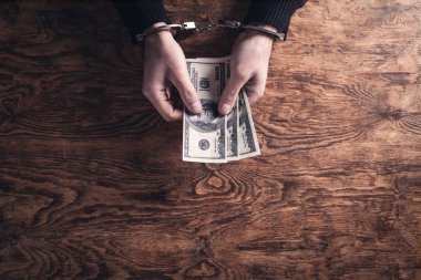 Elleri kelepçeli, ellerinde dolar banknotları var. Yozlaşma