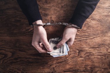 Elleri kelepçeli, ellerinde dolar banknotları var. Yozlaşma