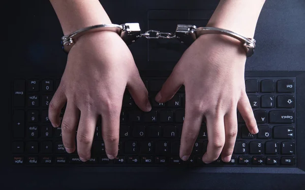 Elleri kelepçeli klavyede yazarak. Siber suç kavramı