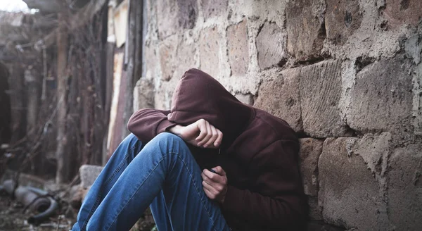 Beyaz evsiz adam oturuyor ve düşünme. 