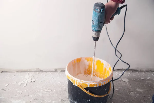 Hombre con un taladro mezclando pintura. Renovación — Foto de Stock