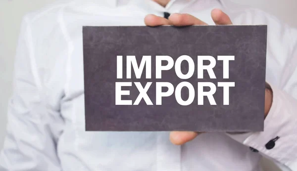 Man holding Import and Export words on cardboard.