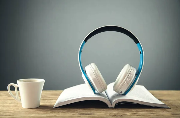 Auriculares y libro en mesa de madera. Concepto de audio libro — Foto de Stock