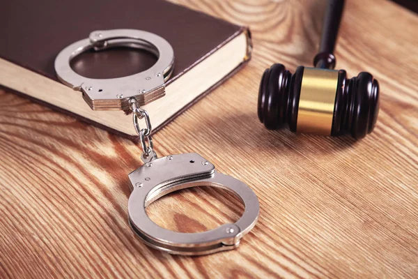 Metal handcuffs and judge gavel on wooden background. Crime and — Stock Photo, Image