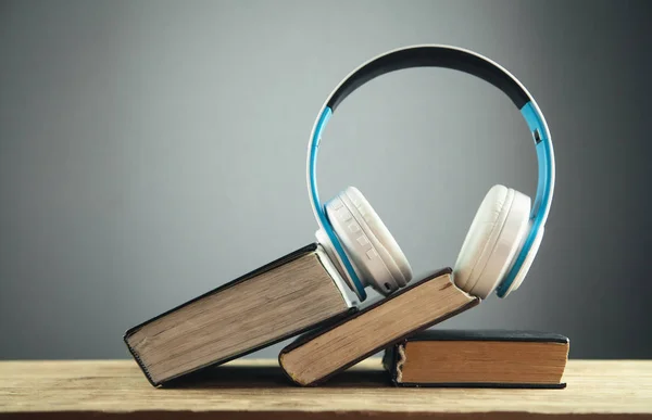Auriculares y libro en mesa de madera. Concepto de audio libro — Foto de Stock