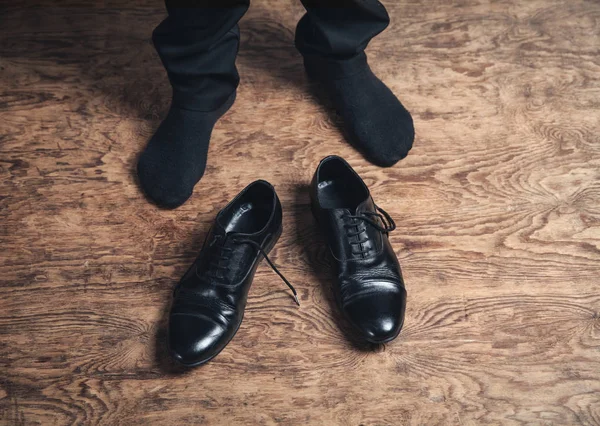 Man fötter med svarta Läders kor på trä golv. — Stockfoto