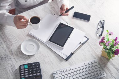 Ofis masasında kahve fincanı tutan iş kızı.