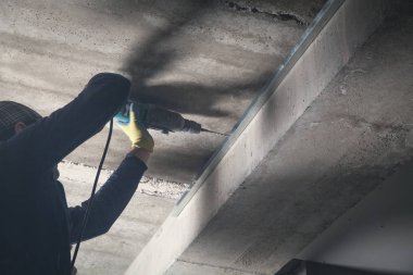 İşçi bir delgiyle duvarı deliyor..