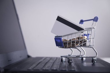 Dizüstü bilgisayar ile alışveriş sepeti ve kredi kartı.