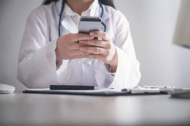 Doktor klinikte cep telefonu kullanarak. 