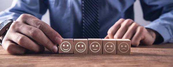 Man showing wooden cube. Rating satisfaction. Feedback in form