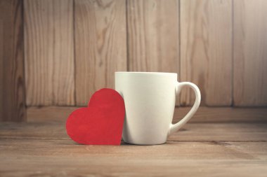 Ahşap arka plan üzerinde kahve fincanı ile kırmızı kalp.