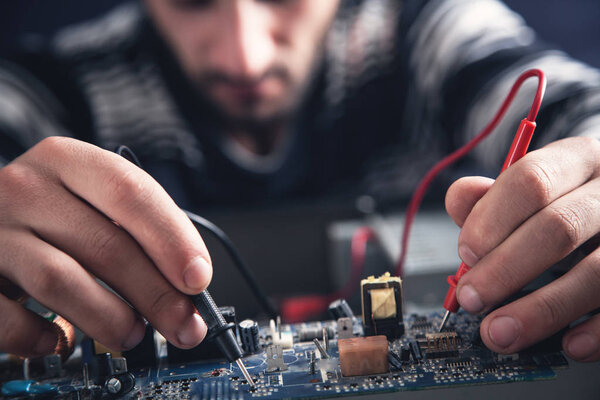 Man checking computer with a multimeter.