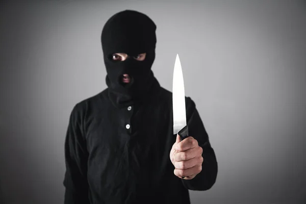 Asesino con máscara negra amenazando con cuchillo. Delito y robo c — Foto de Stock