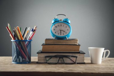 Ahşap masada kitap ve kahve ile çalar saat.