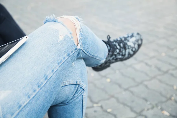 Frau in Jeans sitzt im Park. — Stockfoto