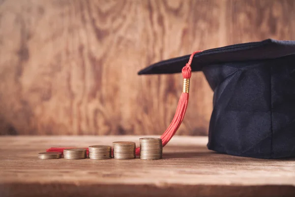 Chapéu de graduação e moedas na mesa de madeira . — Fotografia de Stock