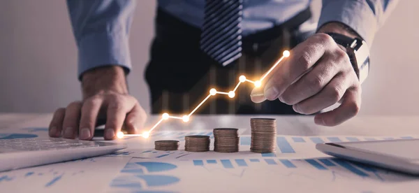 Hombre apilando monedas con un gráfico de ganancias . — Foto de Stock