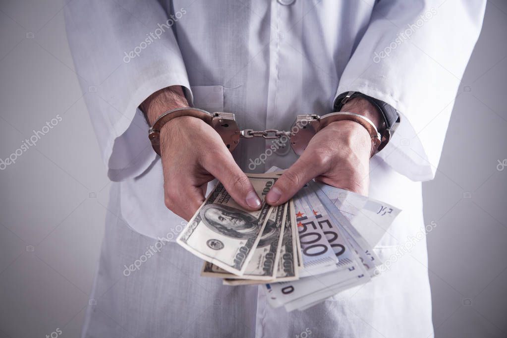 Doctor with handcuffs and money. Medical crime