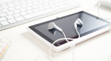 Beyaz masasında kulaklık olan tablet..