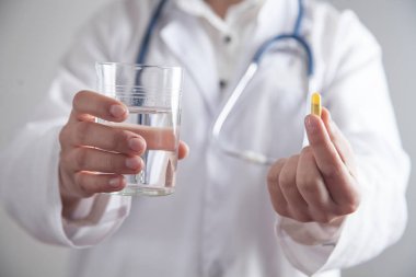 Doktor elinde hap ve bir bardak su tutuyor..