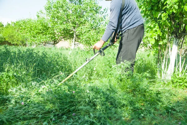 Arbeiter mäht Gras mit einem Rasentrimmer. — Stockfoto