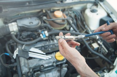 Teknisyen araba motoruna yeni mum yüklüyor.
