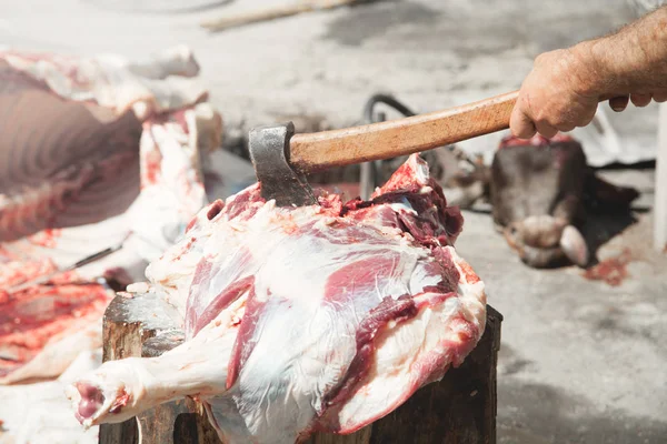 Procesando carne fresca. Carnicero con un hacha en la mano que separa mea — Foto de Stock