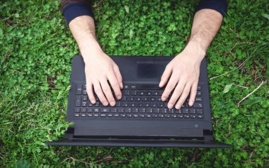 Adam açık içinde laptop yazarak eller.