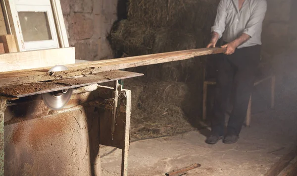 Carpinteiro cortando uma prancha de madeira com uma máquina de carpintaria. — Fotografia de Stock