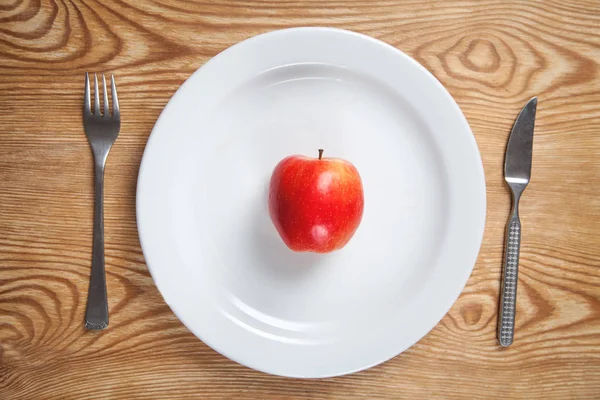 红色苹果在白色板上，用叉子和刀。饮食概念 — 图库照片