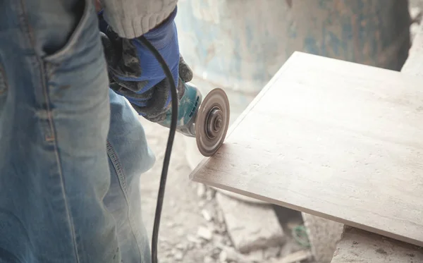 Trabajador cortar una baldosa con una amoladora. — Foto de Stock