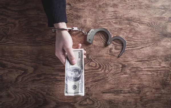 La main dans les menottes tenant des billets en dollars. Corruption — Photo