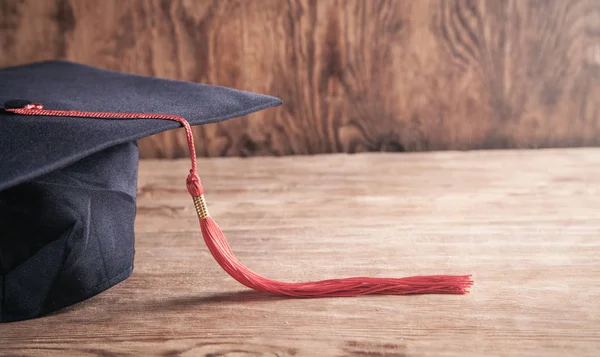 Berretto da laurea sulla scrivania in legno. Istruzione — Foto Stock