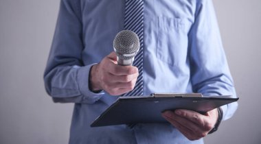 Beyaz işadamı mikrofon tutarak ofiste ayakta.  