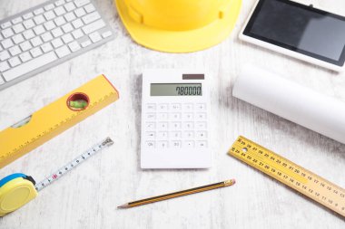Kask, tablet ve diğer nesnelerle ahşap ev modeli.