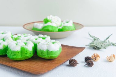 Bir tabak dolusu geleneksel Endonezya çerezi putu ayu, üzerinde hindistan cevizi dilimlenmiş yeşil pandan keki, servis etmeye hazır..