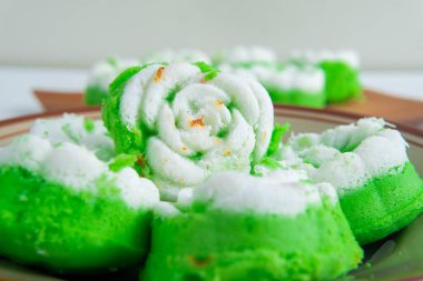 Bir tabak dolusu geleneksel Endonezya çerezi putu ayu, üzerinde hindistan cevizi dilimlenmiş yeşil pandan keki, servis etmeye hazır..