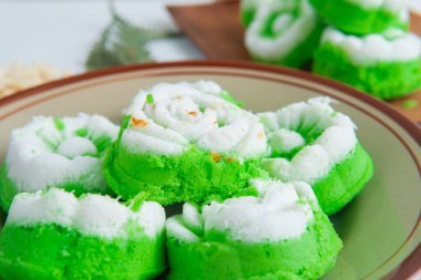 Bir tabak dolusu geleneksel Endonezya çerezi putu ayu, üzerinde hindistan cevizi dilimlenmiş yeşil pandan keki, servis etmeye hazır..