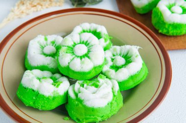 Bir tabak dolusu geleneksel Endonezya çerezi putu ayu, üzerinde hindistan cevizi dilimlenmiş yeşil pandan keki, servis etmeye hazır..