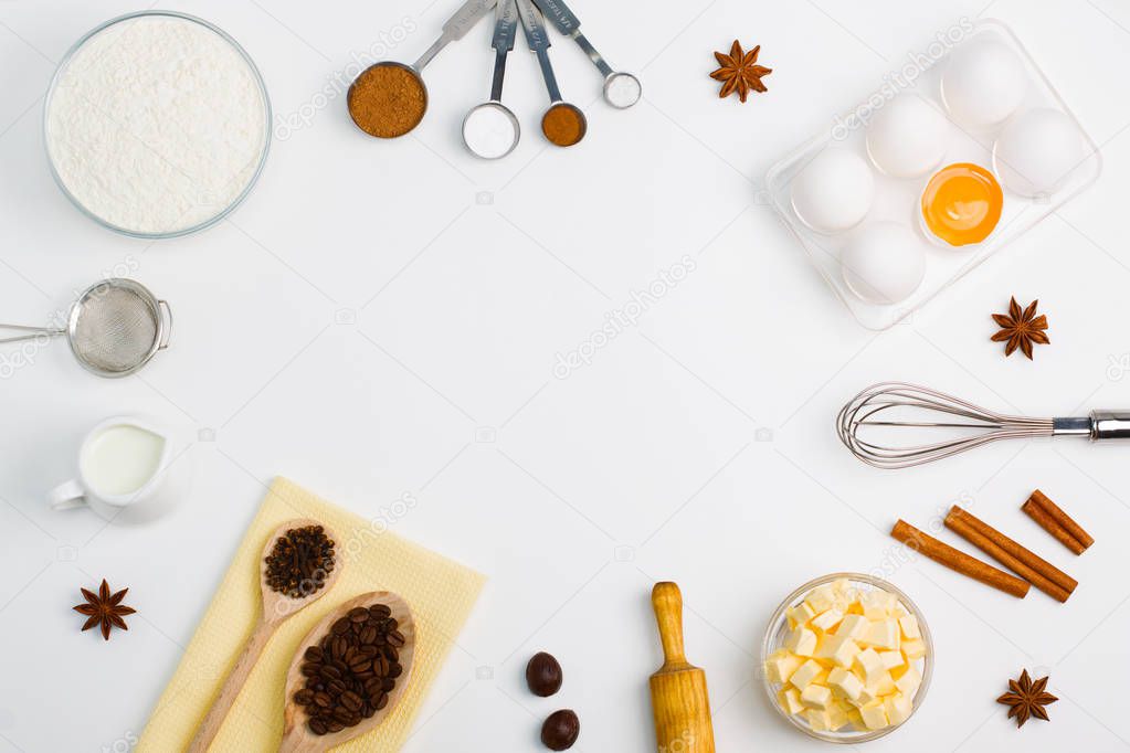 Cooking baking flat lay background with eggs, yolk, a cup of butter, a cup of flour, milk, spices